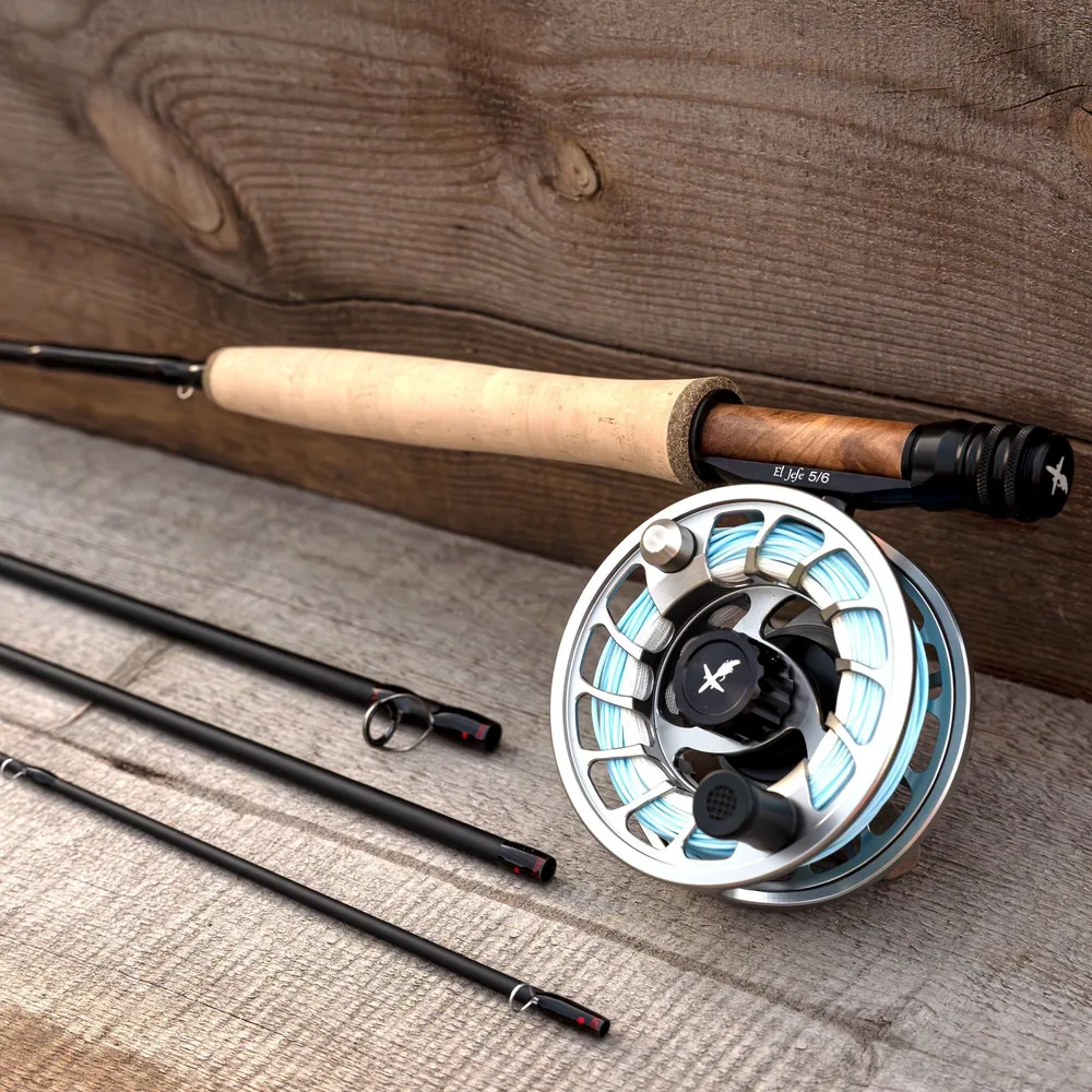 The El Jefe v2 butt section on weathered grey planks, showing the tan cork grip, the wood insert in the machined aluminium reel seat and the El Jefe 5/6 reel, with the three remaining blank sections laid alongside.